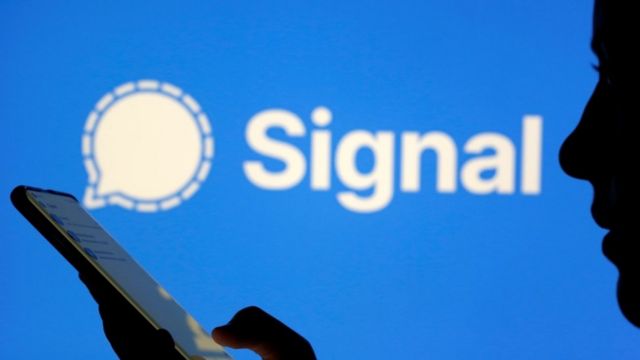 Homem mexendo em celular sim símbolodo Signal ao fundo