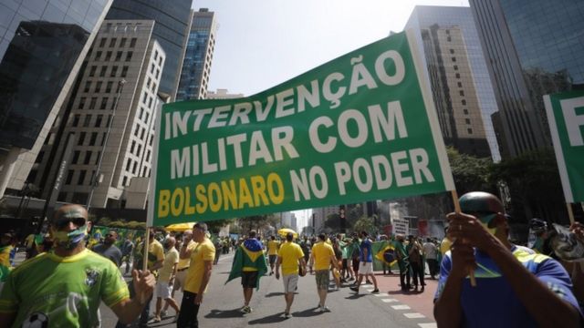 Homens seguram bandeira onde está escrito 'intervenção militar'