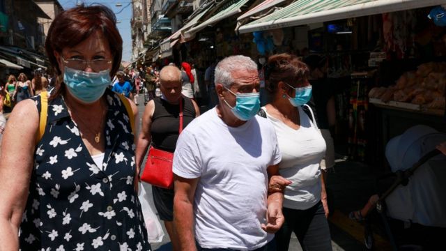 Pessoas andando nas ruas em Israel com máscara facial