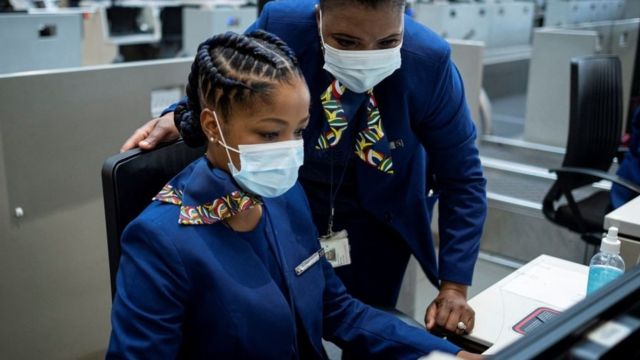 Os funcionários da South African Airways (SAA) fazem o check-in de um passageiro (não visto) no O.R. Aeroporto Internacional de Tambo em Joanesburgo em 23 de setembro de 2021